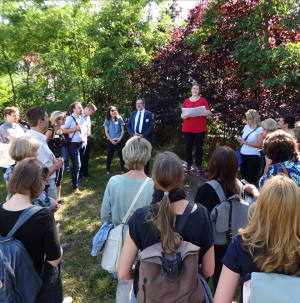 Das Bild zeigt eine Menschenmenge, die im Wald steht und einem Sprecher zuhört.