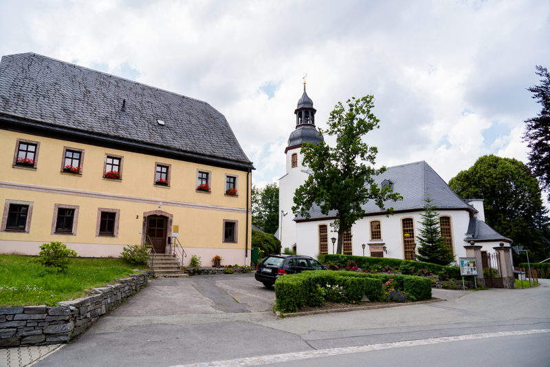 Außenansicht des Kantorat in Auerbach und im Hintergrund sieht man die Auerbach Kirche mit Ihrem Turm