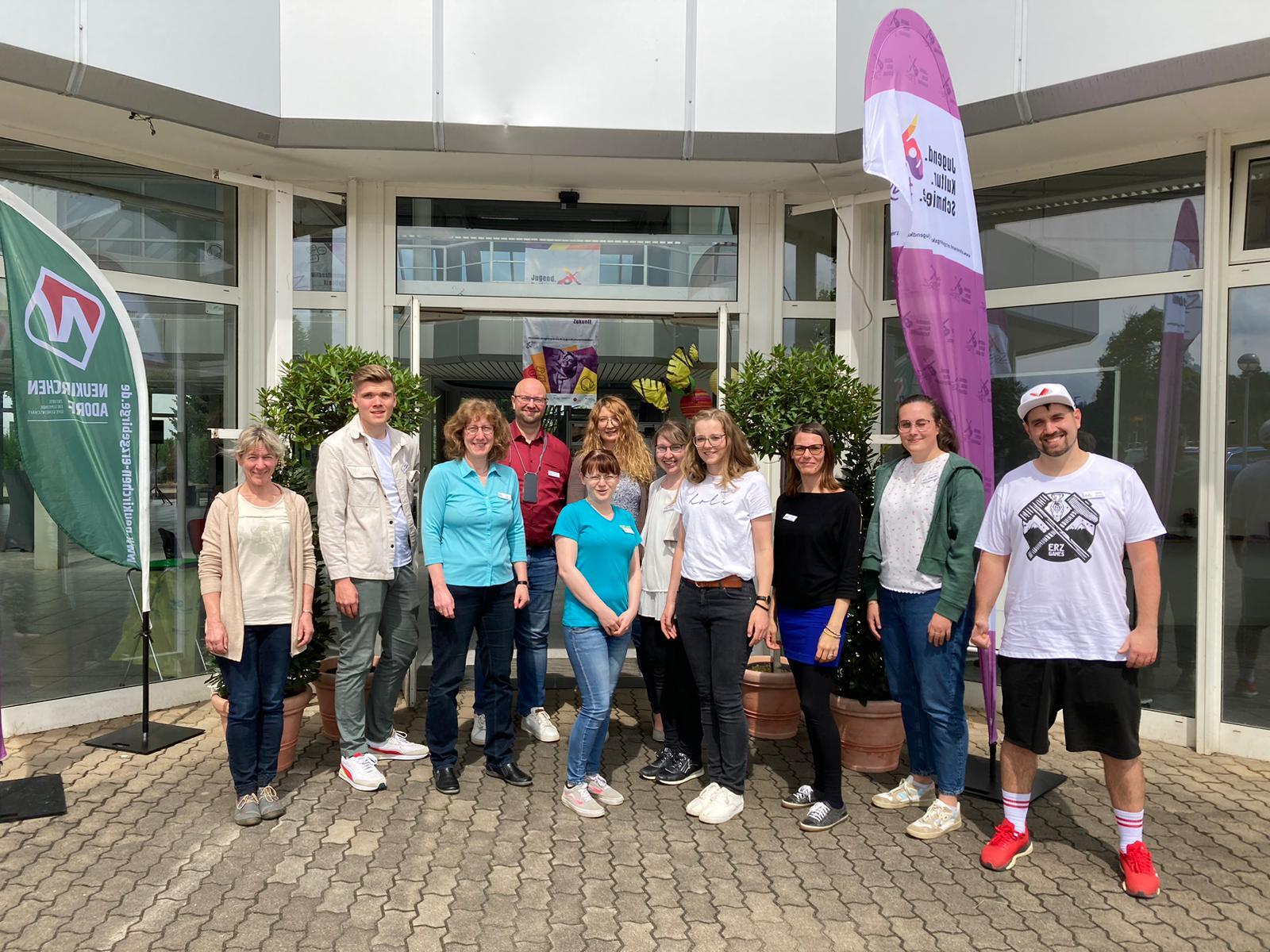 Das Bild zeigt eine Menschengruppe vor einem Hauseingang. Das Bild zeigt eine Menschengruppe vor einem Hauseingang.